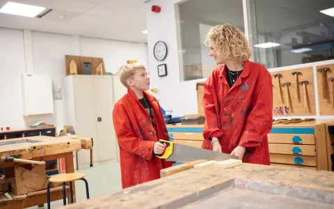 VSO-leerling en docent werken met zaag in het technieklokaal.