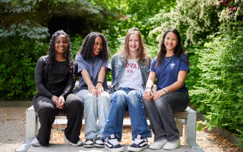 Vier leerlingen op een bankje op het schoolplein van een middelbare school