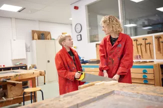 VSO-leerling en docent werken met zaag in het technieklokaal.