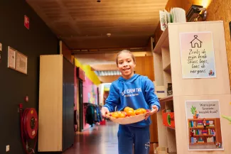 Basisschoolleerling loopt in de hal met een schaal fruit.