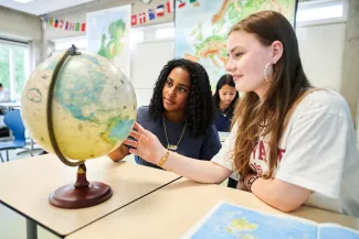 Twee vo-leerlingen kijken samen naar een wereldbol.